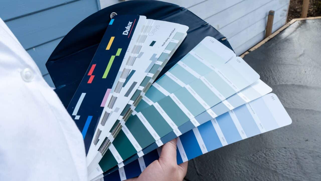 Person holding a color swatch book with various shades of blue and gray.