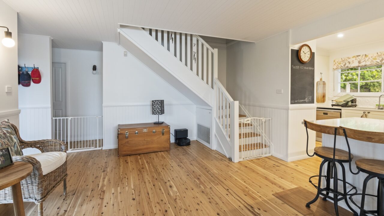 bright living space in a bullaburra house with wooden floors, staircase, and a wooden chest